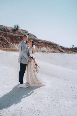 Güzel ve genç gelin ve damat dışarıda poz veriyor.