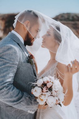 Güzel ve genç gelin ve damat dışarıda poz veriyor.