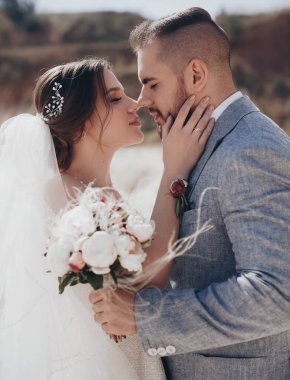 Güzel ve genç gelin ve damat dışarıda poz veriyor.