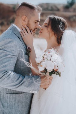 Güzel ve genç gelin ve damat dışarıda poz veriyor.