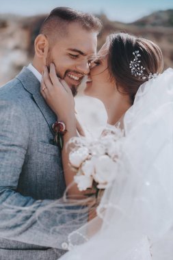 Güzel ve genç gelin ve damat dışarıda poz veriyor.