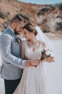 Güzel ve genç gelin ve damat dışarıda poz veriyor.