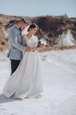 Güzel ve genç gelin ve damat dışarıda poz veriyor.