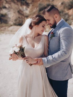 Güzel ve genç gelin ve damat dışarıda poz veriyor.