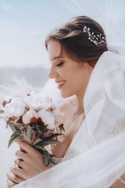 Beyaz gelinlikli güzel gelin dışarıda poz veriyor.