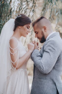 Güzel ve genç gelin ve damat dışarıda poz veriyor.