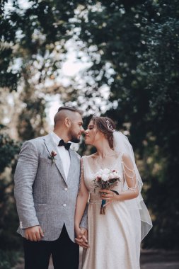 Güzel ve genç gelin ve damat dışarıda poz veriyor.