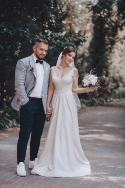 Güzel ve genç gelin ve damat dışarıda poz veriyor.