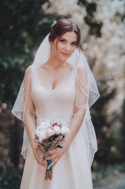 Beyaz gelinlikli güzel gelin dışarıda poz veriyor.