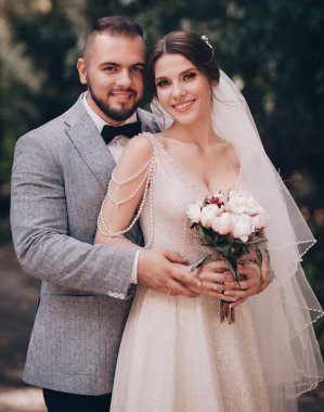 Güzel ve genç gelin ve damat dışarıda poz veriyor.