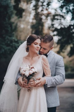 Güzel ve genç gelin ve damat dışarıda poz veriyor.