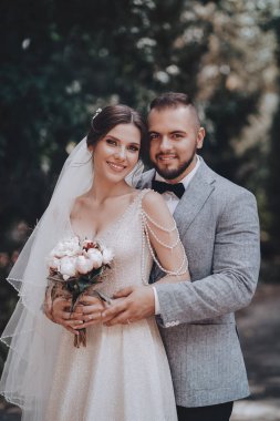 Güzel ve genç gelin ve damat dışarıda poz veriyor.