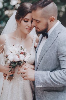 Güzel ve genç gelin ve damat dışarıda poz veriyor.