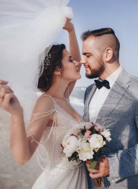 Güzel ve genç gelin ve damat dışarıda poz veriyor.