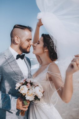 Deniz kenarında poz veren güzel ve genç gelin ve damat