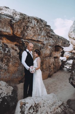 Güzel ve genç gelin ve damat dışarıda poz veriyor.