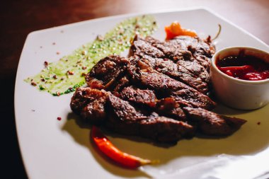 Beyaz tabakta sebze soslu biftek.