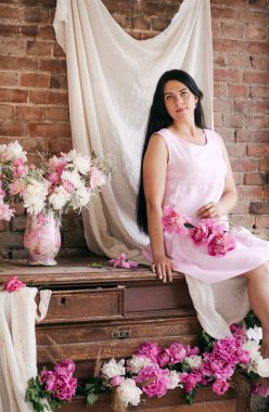 Stüdyoda şakayıklarla poz veren güzel bir genç kadın.