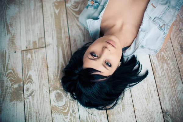 Erotic portrait of a beautiful girl lying on a wooden floor — Stock Photo, Image