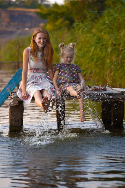 Madre e hija sentadas en el muelle — Foto de Stock