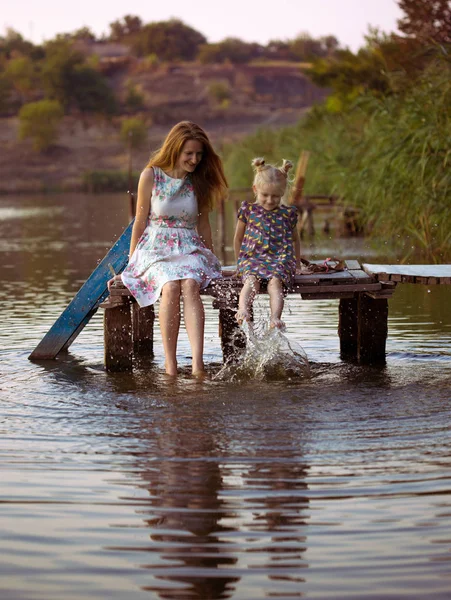 Anne ve kızı iskelede oturup — Stok fotoğraf
