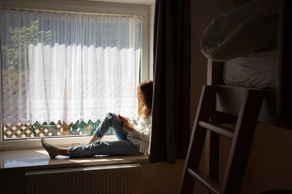 Tonåring flicka sitter på fönsterblecket — Stockfoto