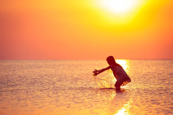 夕焼けの海を歩いて子供の女の子 — ストック写真