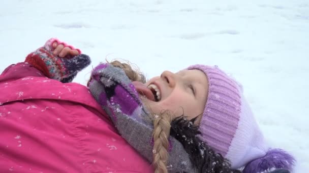 Bambino ragazza cattura un fiocchi di neve con la lingua close up video — Video Stock