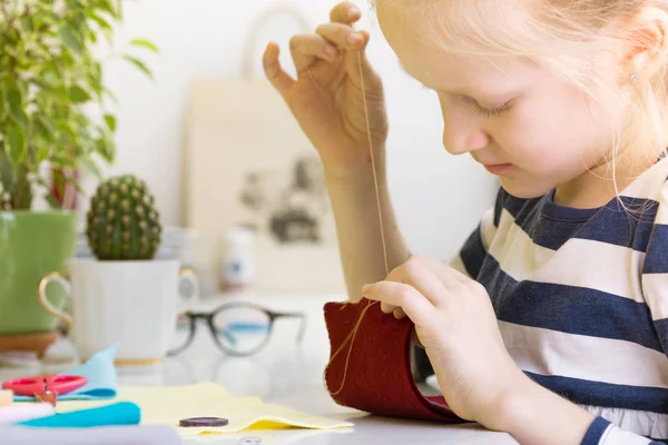 Little girl sews toy — Stock Photo, Image