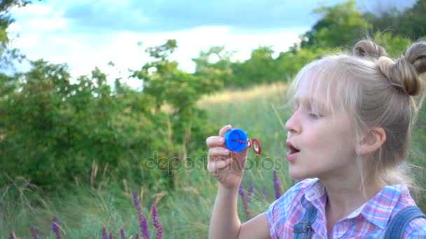 Liten flicka blåser såpbubblor på en grön gräsmatta — Stockvideo