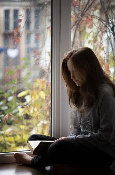 Teen girl sitting on a windowsill — Stock Photo, Image