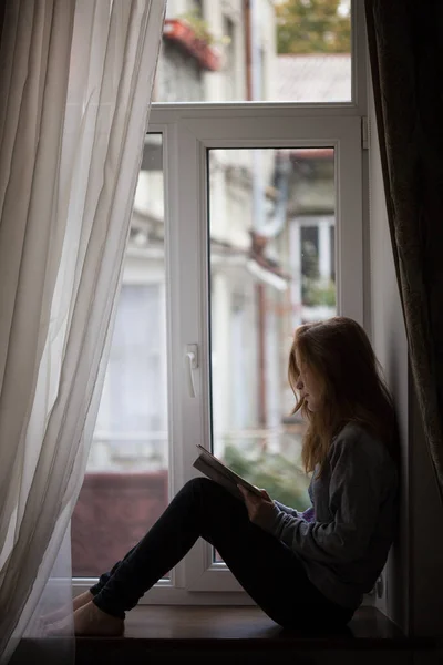Menina adolescente sentada em uma janela — Fotografia de Stock