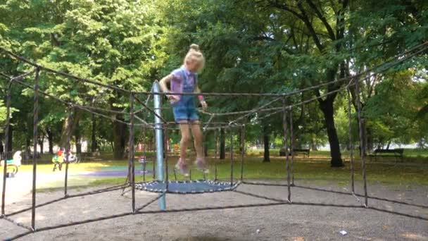 Criança menina pulando no playground no parque — Vídeo de Stock