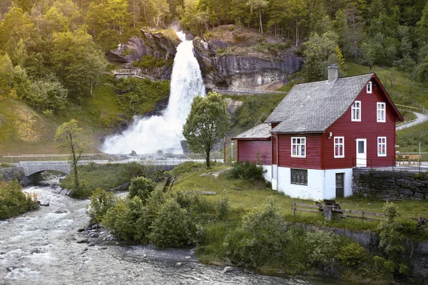 Traditionelles norwegisches rotes Holzhaus und steinsdalsfossen — Stockfoto