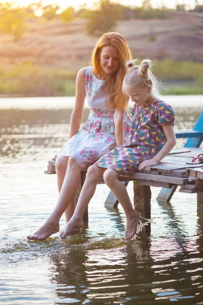 Matka i córka siedzi na molo — Zdjęcie stockowe