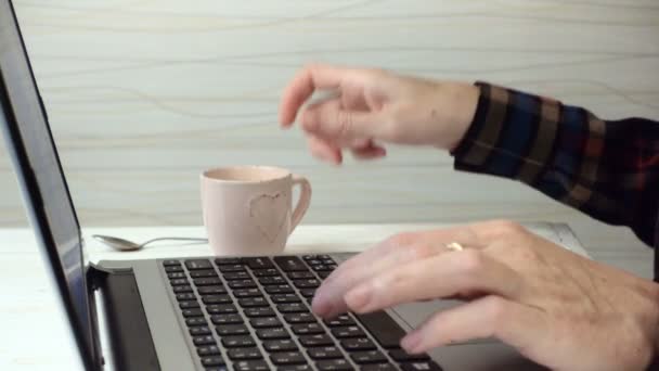 Girl typing on a laptop keyboard and drinking a coffee — Stock Video