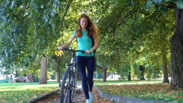 Chica montada en bicicleta por las calles y en el parque de la ciudad — Vídeos de Stock