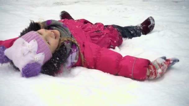 Lächelndes kleines Mädchen, das Spaß am verschneiten Wintertag hat — Stockvideo
