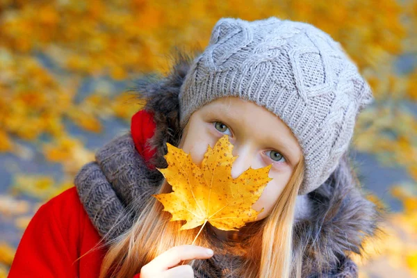 Menina detém uma folha amarela — Fotografia de Stock
