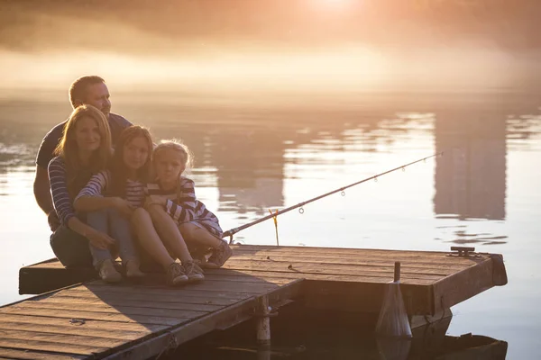 Glückliche Familie sitzt auf der Seebrücke — Stockfoto