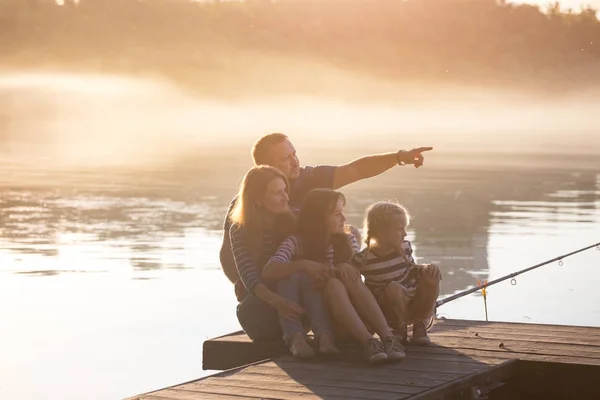 Mutlu aile iskelede oturup — Stok fotoğraf