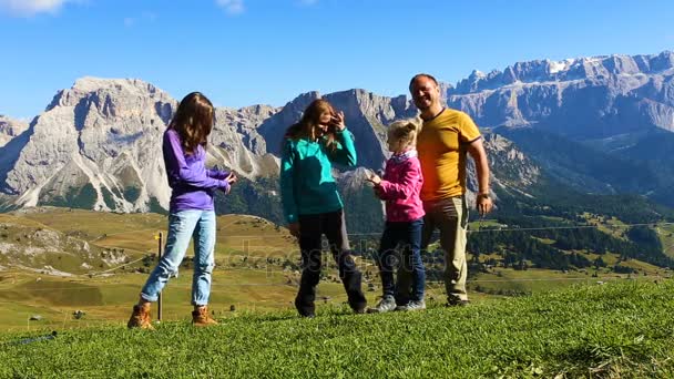 Padres e hijos sentados en una hierba y mirando a las montañas — Vídeos de Stock