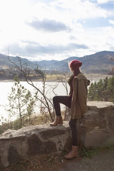 Ragazza hipster si siede sullo sfondo delle montagne — Foto Stock