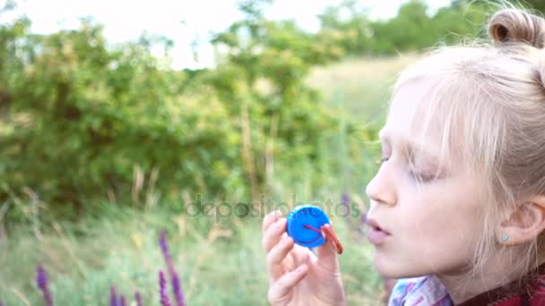 Kleines Mädchen Pustet Seifenblasen Auf Grünem Rasen — Stockvideo