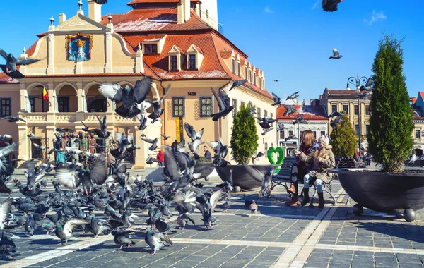 Crianças alimentando pombos em uma praça principal da cidade romena Braso — Fotografia de Stock