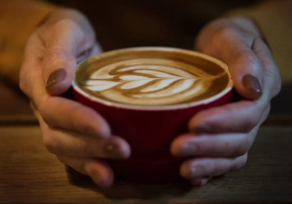 Fille mains tenant tasse rouge de capuccino — Photo