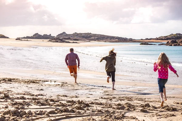 Papa et deux filles courant le long de la plage — Photo