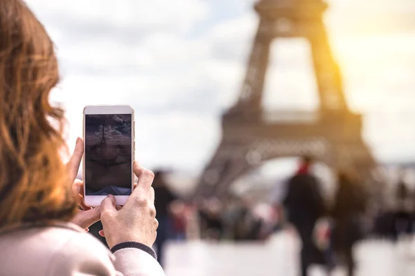 Девушка фотографирует Эйфелеву башню на смартфоне — стоковое фото