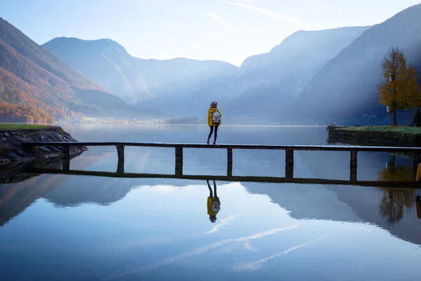 Turista dívka v klobouku a s batohem stojí na dřevěné podprsenky — Stock fotografie