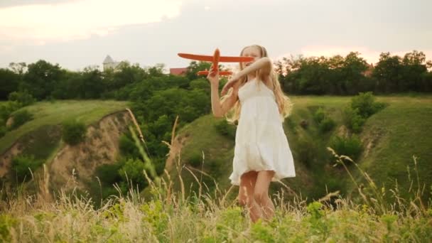小女孩在日落的草地上玩玩具飞机 — 图库视频影像